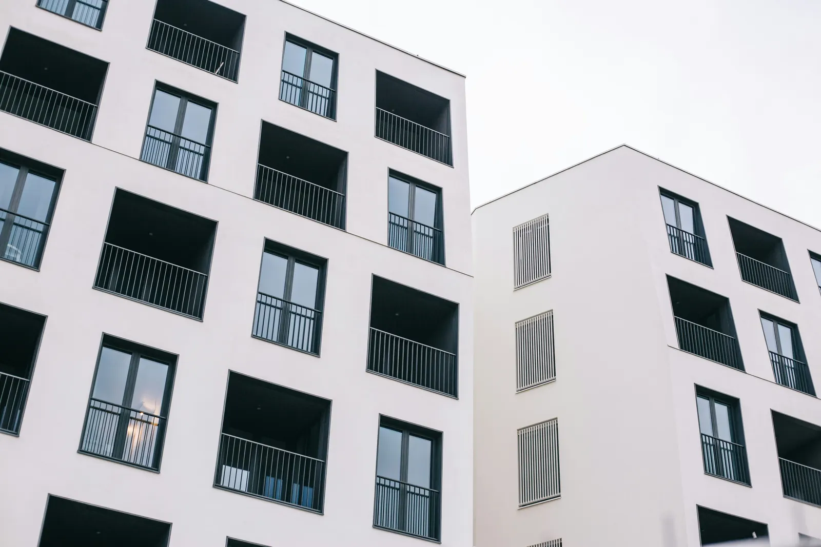 Nybyggt flerbostadshus med vit fasad och svarta balkonger